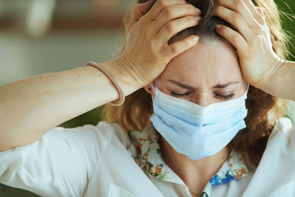 Life during covid-19 pandemic. stressed young woman in white blouse with medical mask. - Фото, изображение