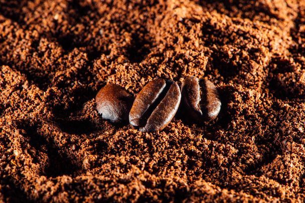 Primer plano granos de café tostados en el café molido, pila de polvo o fondo de café instantáneo
 - Foto, imagen