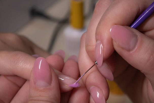 the process of doing manicure. Closeup of hands of professional manicurist, applying nail polish. Concept of doing manicure and fingernails cleaning. beauty concept. Gel polish, shellac. - Photo, Image