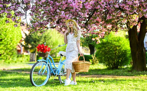 I am free. perfect smell. perfume spa and allergic. travel. retro woman sell tulip flower bouquet. girl under sakura with vintage bicycle. spring beauty and fashion. cherry tree pink blossom - Foto, afbeelding