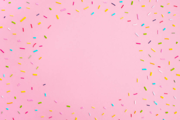 Doux confettis colorés sur fond rose pastel. Composition minimaliste tendance. Fête d'anniversaire, célébration, maquette pour le design. Vue du dessus, cadre, plan, espace de copie - Photo, image