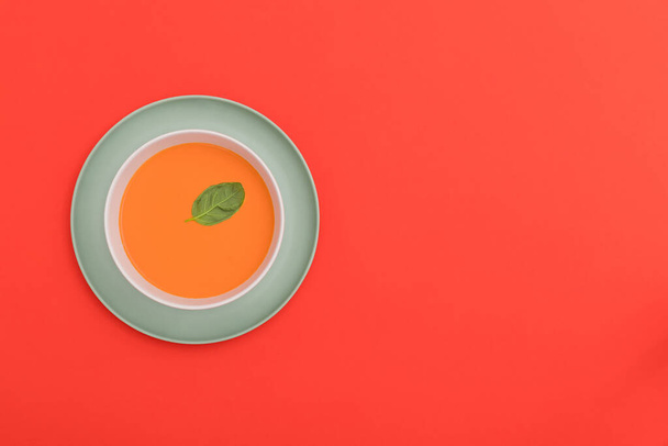 Gazpacho bílá mísa na modrém talíři na červeném pozadí. Horní pohled. Kopírovat prostor. - Fotografie, Obrázek