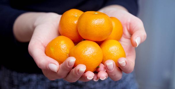 The girl holds tangerines in her hands. Consumption of fruits rich in vitamins - Foto, Imagem
