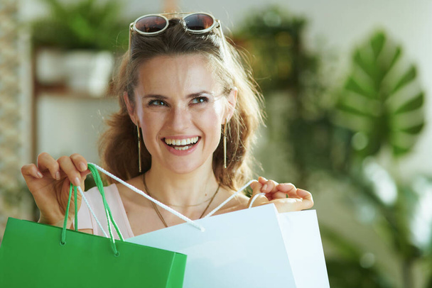 happy trendy female shopper in sunglasses with paper shopping bags. - Фото, зображення