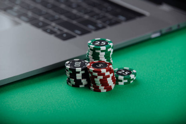 Casino chips y portátil sobre fondo verde. Casino concepto en línea
 - Foto, imagen
