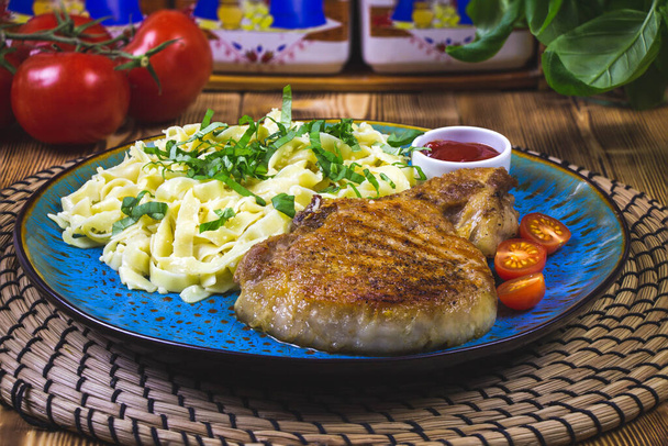 juicy grilled pork chop with greens and pasta. - Photo, Image