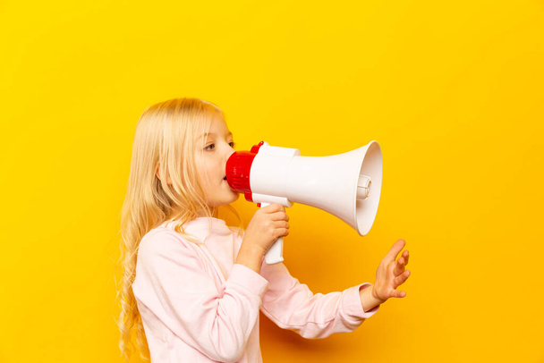 Ένα παιδί να φωνάζει μέσα από μεγάφωνο. Σχέδιο επικοινωνίας. κίτρινο φόντο ως αντίγραφο χώρου για το κείμενό σας - Φωτογραφία, εικόνα