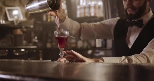 Prise de vue rapprochée. Le barman verse l'alcool du shaker à travers une passoire dans le verre. 4k - Séquence, vidéo