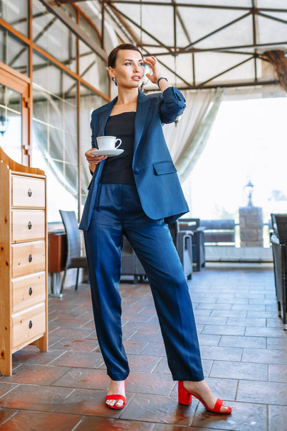 Business girl in a blue suit, resting in a restaurant - Fotó, kép
