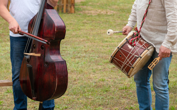 Banda rural tocando al aire libre. Músicos con contrabajo y tambores actuando en la hierba afuera
 - Foto, imagen