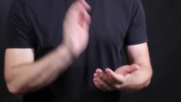 Manos masculinas caucásicas en una camiseta negra de manga corta, palmadas en la palma
 - Metraje, vídeo