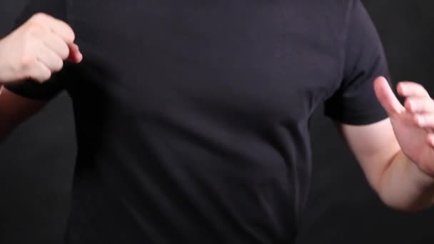 Manos masculinas caucásicas en una camiseta negra de manga corta, tirando de un puño
  - Metraje, vídeo
