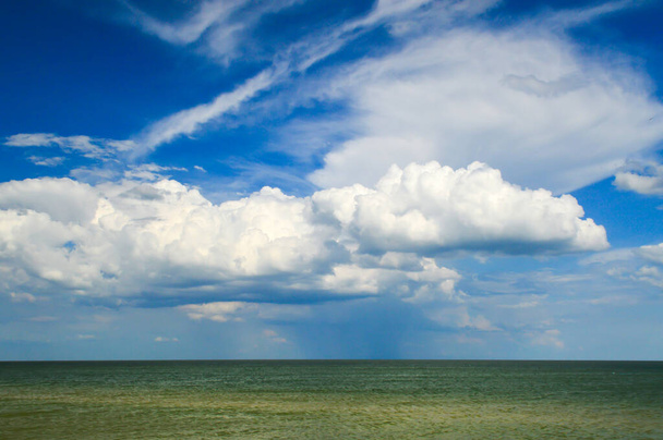 Una gran nube blanca exuberante sobre la superficie azul del agua de mar
 - Foto, imagen