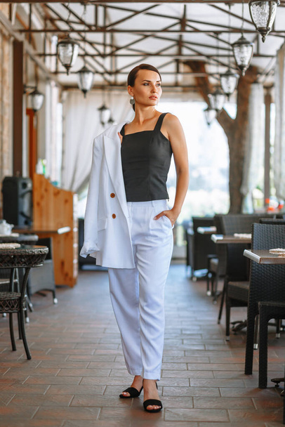 Business girl in a white suit in the lobby of a restaurant. Demonstration of clothing - Фото, зображення