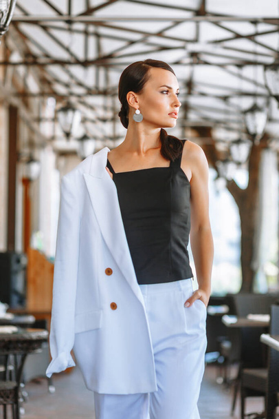 Business girl in a white suit in the lobby of a restaurant. Demonstration of clothing - Fotoğraf, Görsel