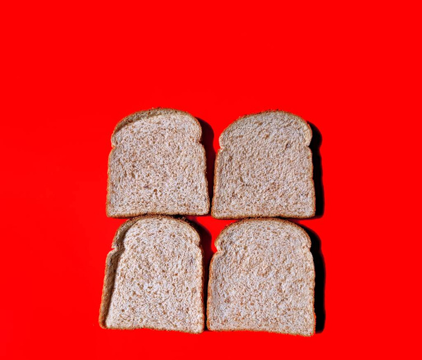 Plátky celozrnného chleba na červeném pozadí. zdravá výživa - Fotografie, Obrázek