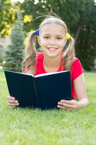 Summer reading club. Happy girl read book on green grass. Summer reading list. Summer vacation. School holidays. Recreation and leisure. Read more this summer - Fotó, kép