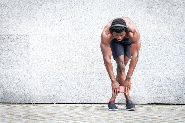 Afrikaans-Amerikaanse sportman die buiten tegen de muur traint, atleet die zonder t-shirt traint, kopieert ruimte - Foto, afbeelding