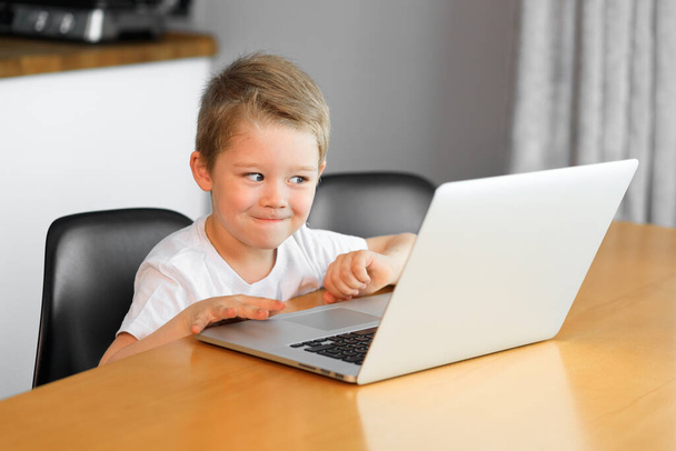 A little boy watches an educational video on a new laptop - Zdjęcie, obraz