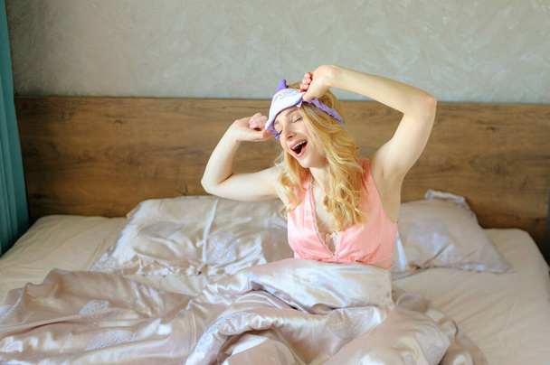 若いです女性とともに長いですブロンド髪とともに睡眠マスク上の彼女の頭の上に目覚め - 写真・画像