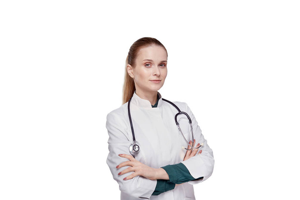 Kaunis nuori nainen lääkäri valkoisessa lääketieteellisessä takissa katselee kameraa. - Valokuva, kuva