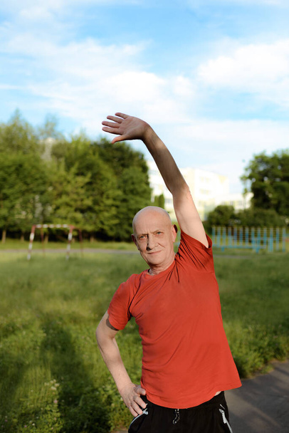 Yaşlı bir adam parkta egzersiz yapıyor da. Aktif ve sağlıklı yaşam tarzı. - Fotoğraf, Görsel