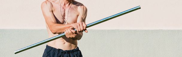 A middle aged man exercises with a metal pole - Fotoğraf, Görsel
