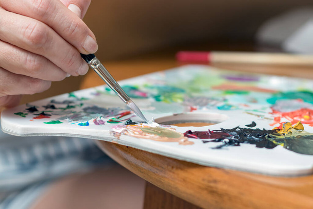 Nainen taiteilija käsi sekoittamalla värejä siveltimellä väripaletti - Valokuva, kuva