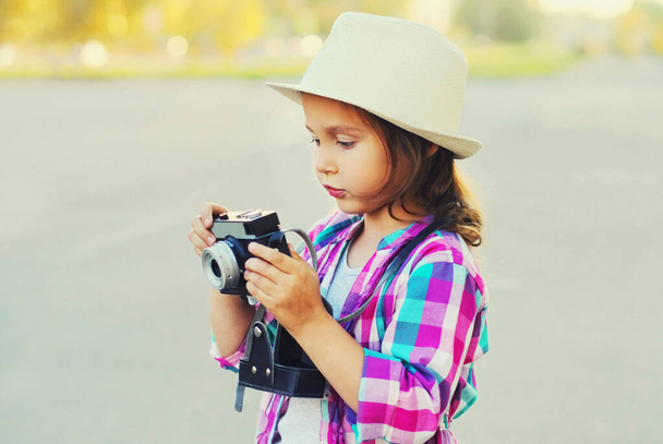 Close up child with retro camera taking picture wearing a summer straw hat outdoors - Photo, Image