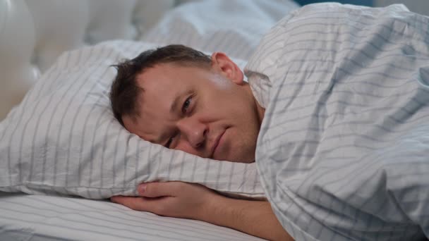 Ein Mann liegt auf dem Bett, wirft und dreht sich, kann nicht schlafen, steht auf - Filmmaterial, Video
