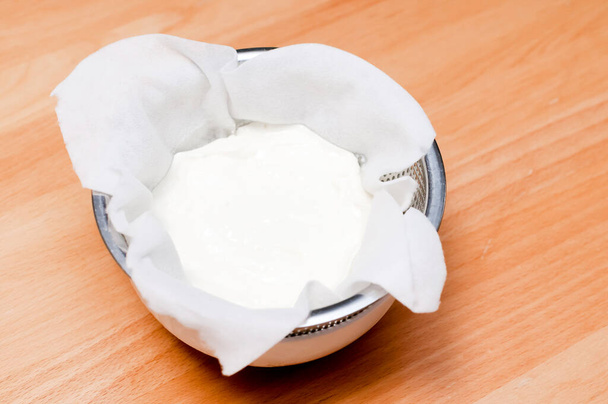 yogur griego hecho a mano, escurrir agua (suero) de yogur para hacer yogur griego
. - Foto, Imagen