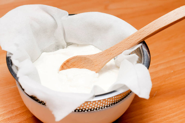 yogur griego hecho a mano, escurrir agua (suero) de yogur para hacer yogur griego
. - Foto, imagen