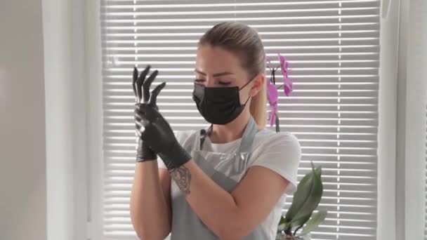 Kosmetikerin zieht schwarze Gummihandschuhe über seine Hände. - Filmmaterial, Video