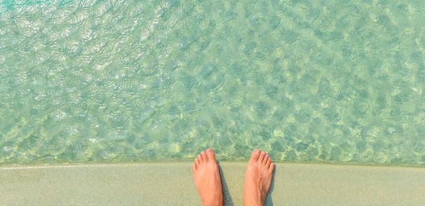 Pied nu de l'homme debout sur le bord de la piscine bleu vif, avec de l'eau avec réflexion de la lumière du soleil, vacances, détente, concept d'escapade - Photo, image
