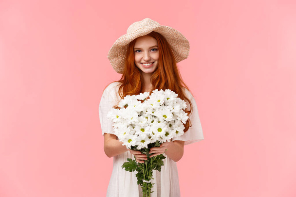 Se on sinulle, onneksi olkoon. Viettelevä kaunis nuori karismaattinen punapää tyttö antaa kimpun valkoisia kukkia ja hymyilee, onnittelut syntymäpäivä, ilmaista rakkautta ja huolenpitoa, pysyvä vaaleanpunainen tausta - Valokuva, kuva