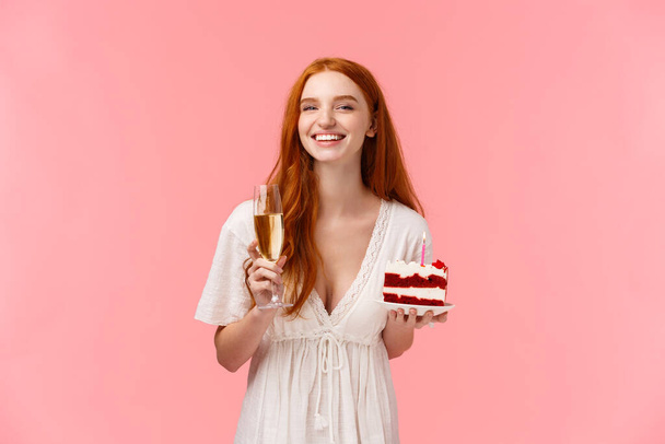 Innoissaan, huoleton ja onnellinen söpö punapää nainen, jolla on pitkä kihara kampaus, valkoinen mekko, nostamalla lasi samppanjaa hurraa, juhlii syntymäpäivää, pitää rauhaa b-päivän kakku, nauraa iloisesti - Valokuva, kuva