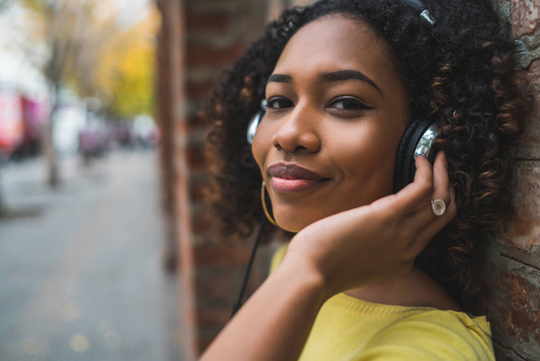 Portrait of young Afro american woman listening to music with headphones in the street. Outdoors. - Foto, Bild