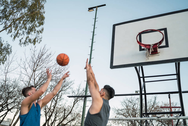 Young basketball players playing one-on-one on outdoor court. Sport and basketball concept. - Photo, Image