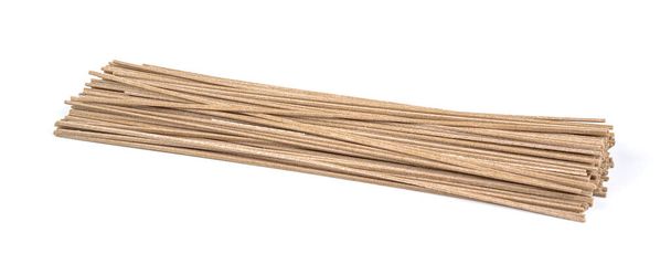 Gedroogde rauwe Japanse soba noodle sticks geïsoleerd op een witte achtergrond. - Foto, afbeelding