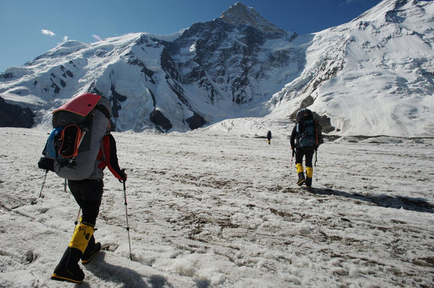Khan Tengri / Καζακστάν - 07.27.2011: Αναρριχητές πηγαίνουν στους πρόποδες του βουνού Khan Tengri. Η αρχή της ανάβασης στην κορυφή. - Φωτογραφία, εικόνα