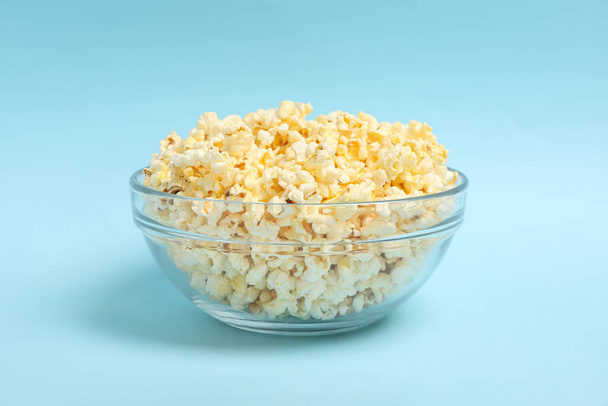 Bowl with popcorn on blue background. Food for watching cinema - Fotoğraf, Görsel