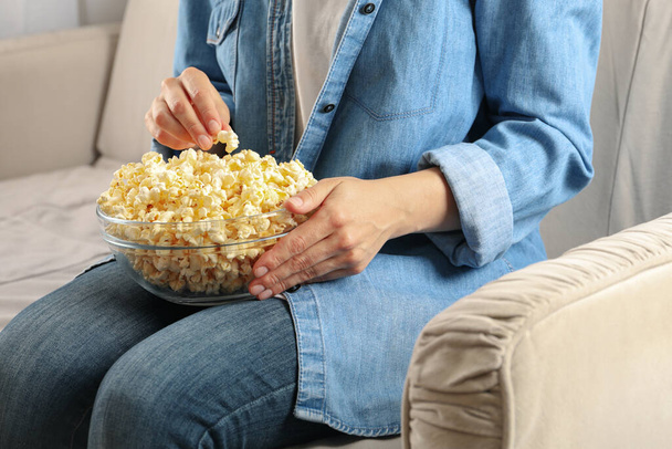 Woman watching film on sofa and eat popcorn. Food for watching films - Фото, изображение