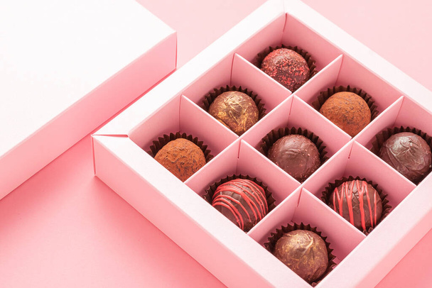 Csokis szarvasgomba cukorka dobozos rózsaszín háttérrel. Ajándékok ünnepi étel szerelem koncepció. Vízszintes képkocka másolási tér . - Fotó, kép