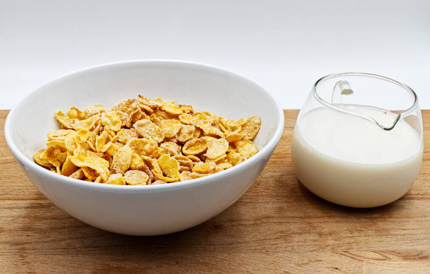 Tál kukoricapelyhekkel és tejjel a fa asztalon - Fotó, kép