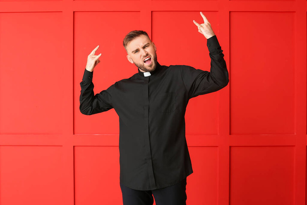 Cool young priest on color background - Foto, afbeelding
