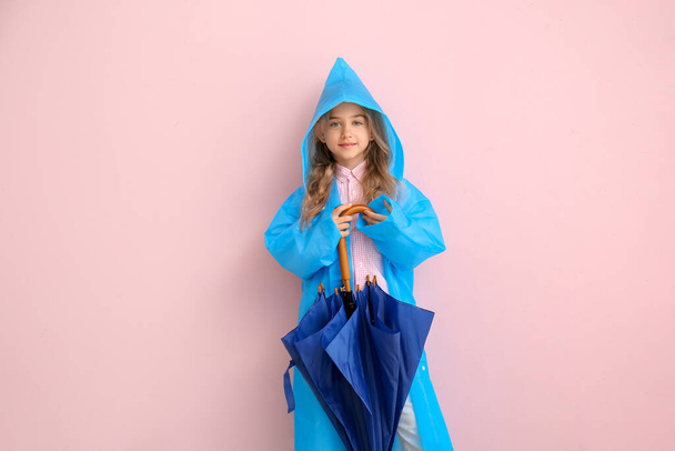 Χαριτωμένο κοριτσάκι με αδιάβροχο και ομπρέλα στο φόντο χρώμα - Φωτογραφία, εικόνα