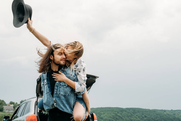 Young Trendy Traveling Couple Having Fun Near the Car on Top of Hill Travel and Road Trip Concept - Photo, Image