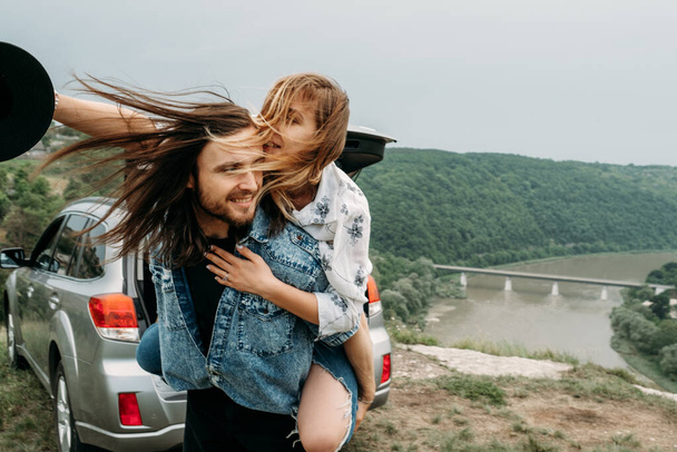 Jovem na moda viajando casal se divertindo perto do carro no topo do Hill Travel e Road Trip Concept
 - Foto, Imagem