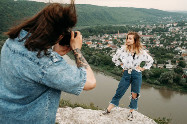 Trendy fotograaf maakt foto shoot van stijlvol meisje in grunge kleding - Foto, afbeelding