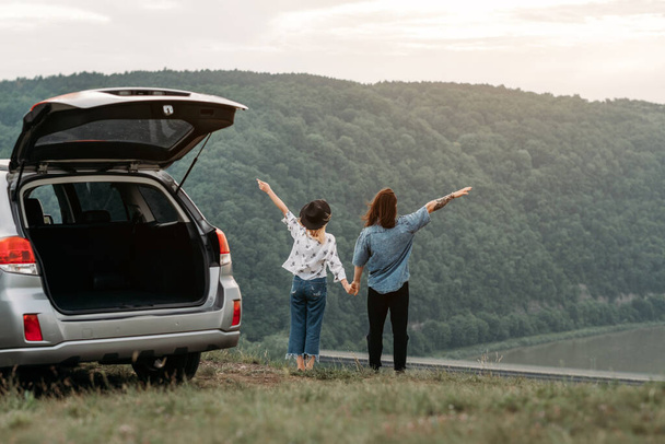 Young Trendy Traveling Couple Having Fun Near the Car on Top of Hill Travel and Road Trip Concept - Photo, Image